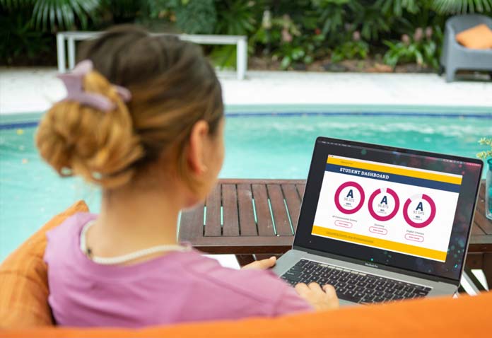 A girl using a computer by a pool