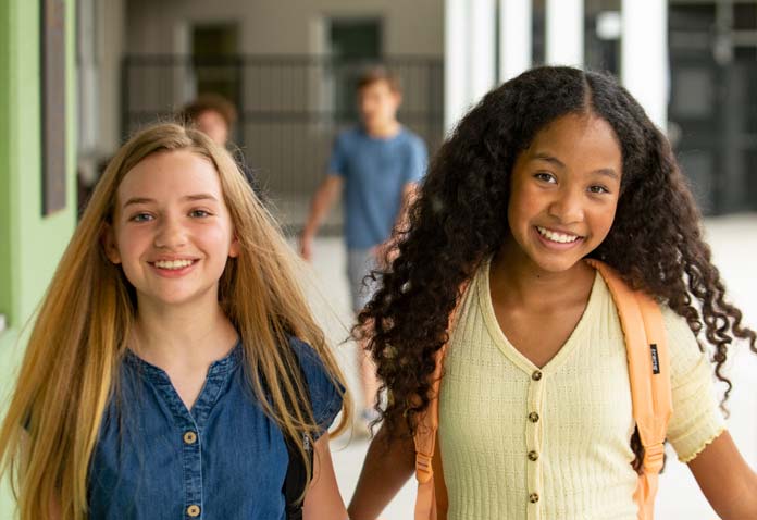 Two girls wearing backpacks and smiling