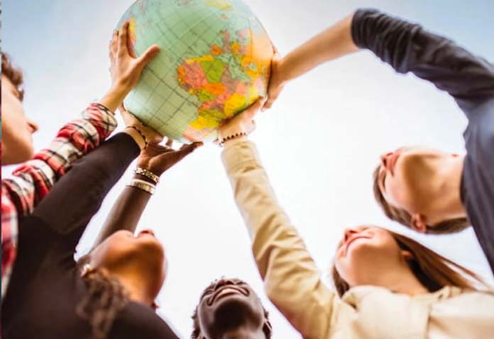 Students reaching up to hold a globe between them