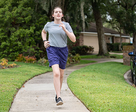 girl running down sidewalk in neighborhood